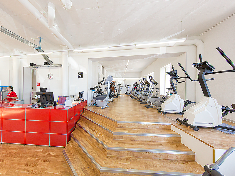 Ausdauergeräte, Velos oberhalb von Treppe neben Tresen in ACTIV FITNESS Studio Corcelles